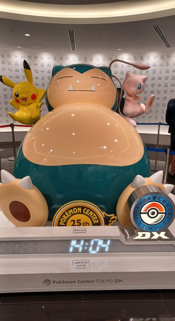 3 statues of Pikachu (small) on the left, Snorlax (large) in the middle, and Mew (small) on the right. Pikachu and Mew are next to Snorlax's head. 