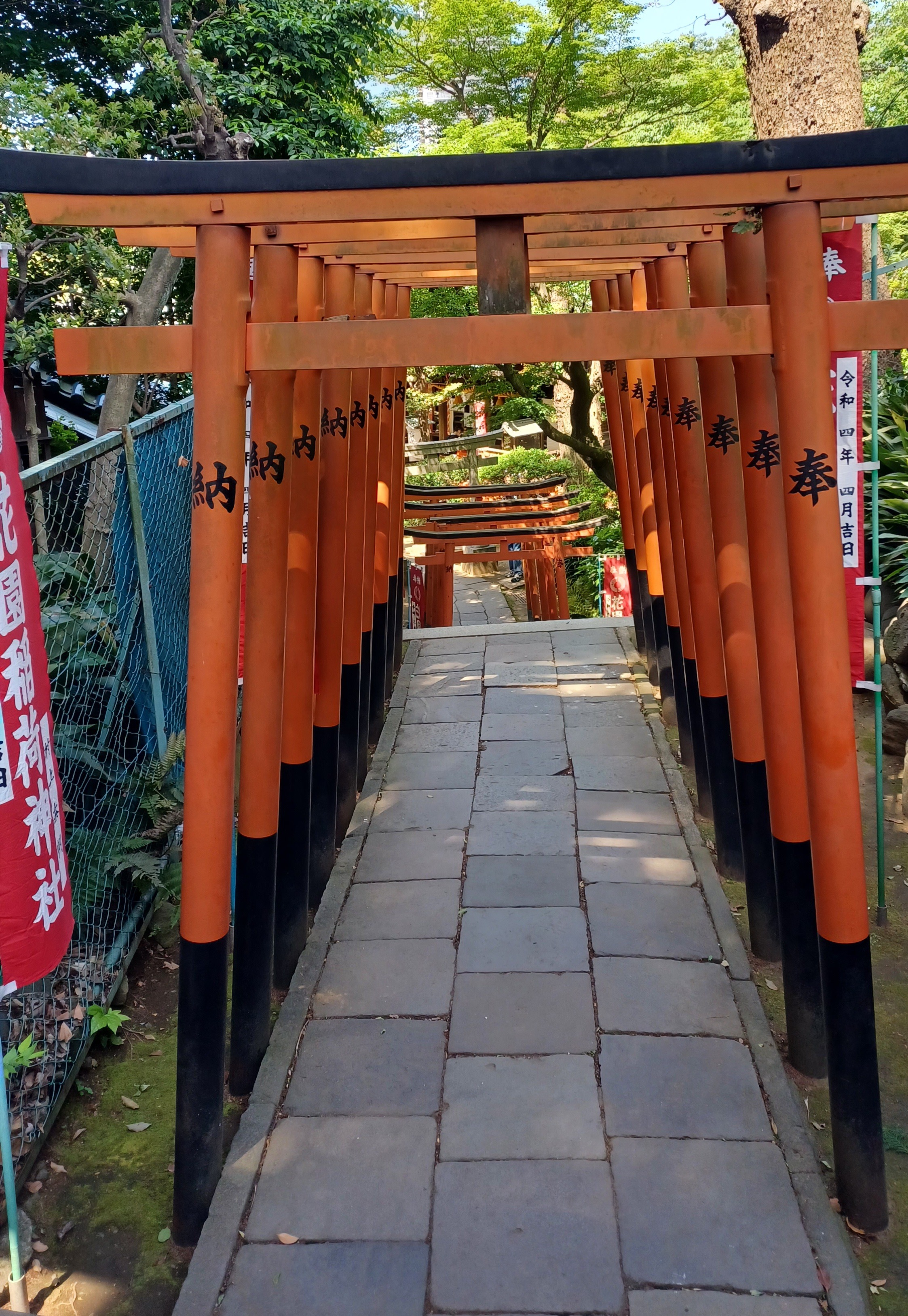 A tunnel of orange/red torii gates with a black Japanese symbol written on each one.