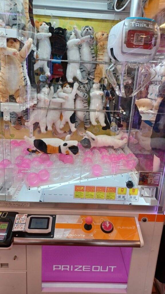 An UFO catcher machine with cat plushies to be won.
