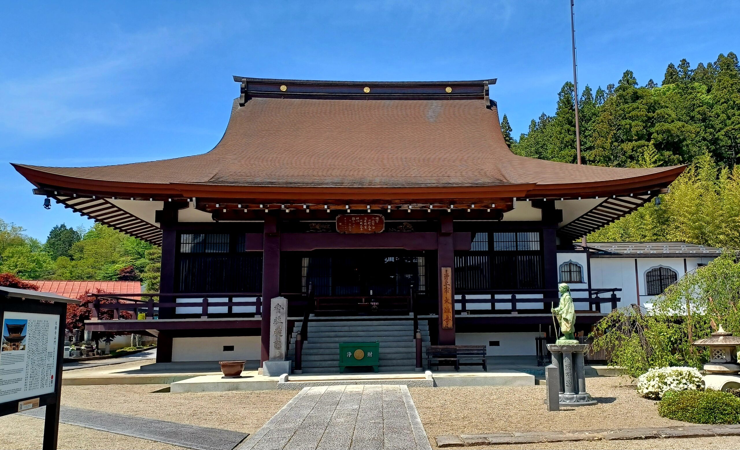 A dark brown Buddhist temple building with a red roof.