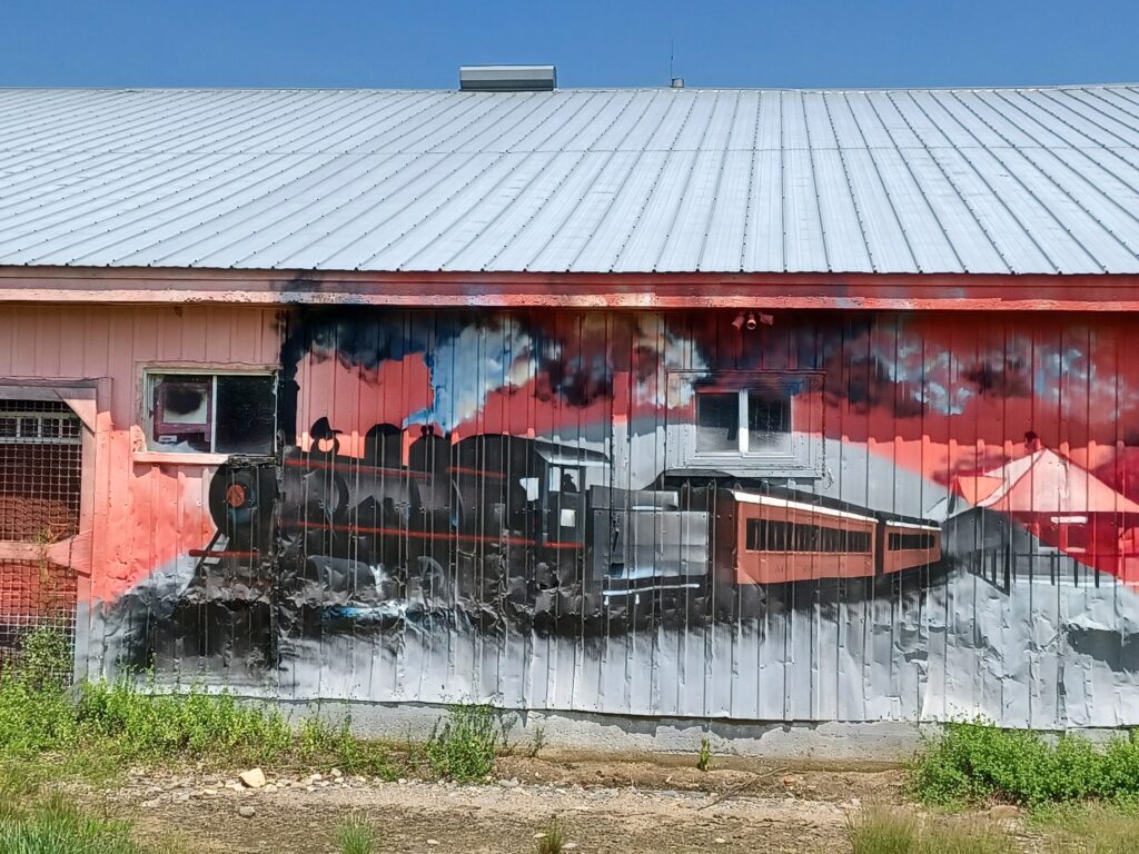 A painting of a steam locomotive train on a house wall, red background.