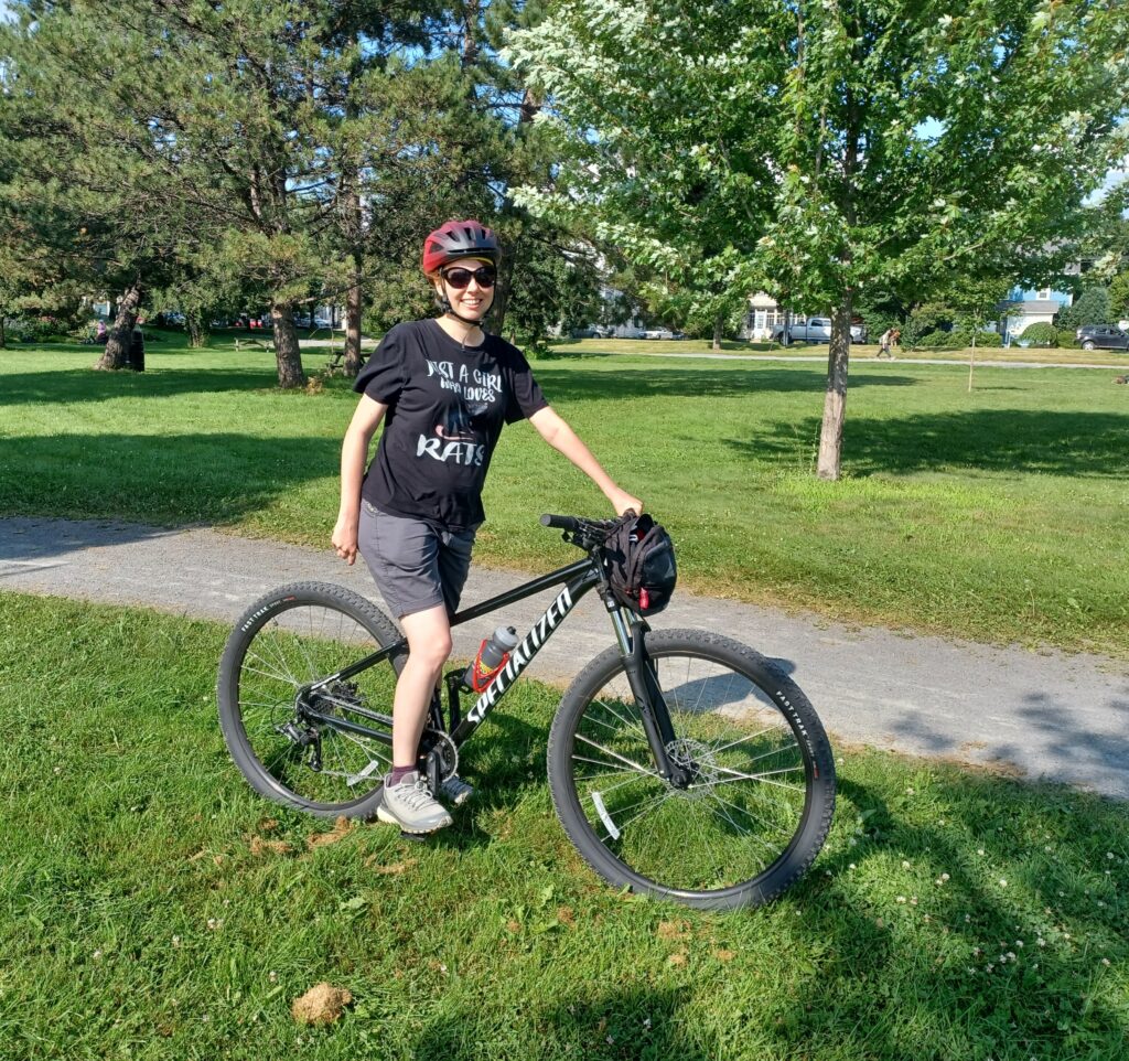 Me sitting on a black bike of the Specialized brand. There are grassy areas and trees in the background.