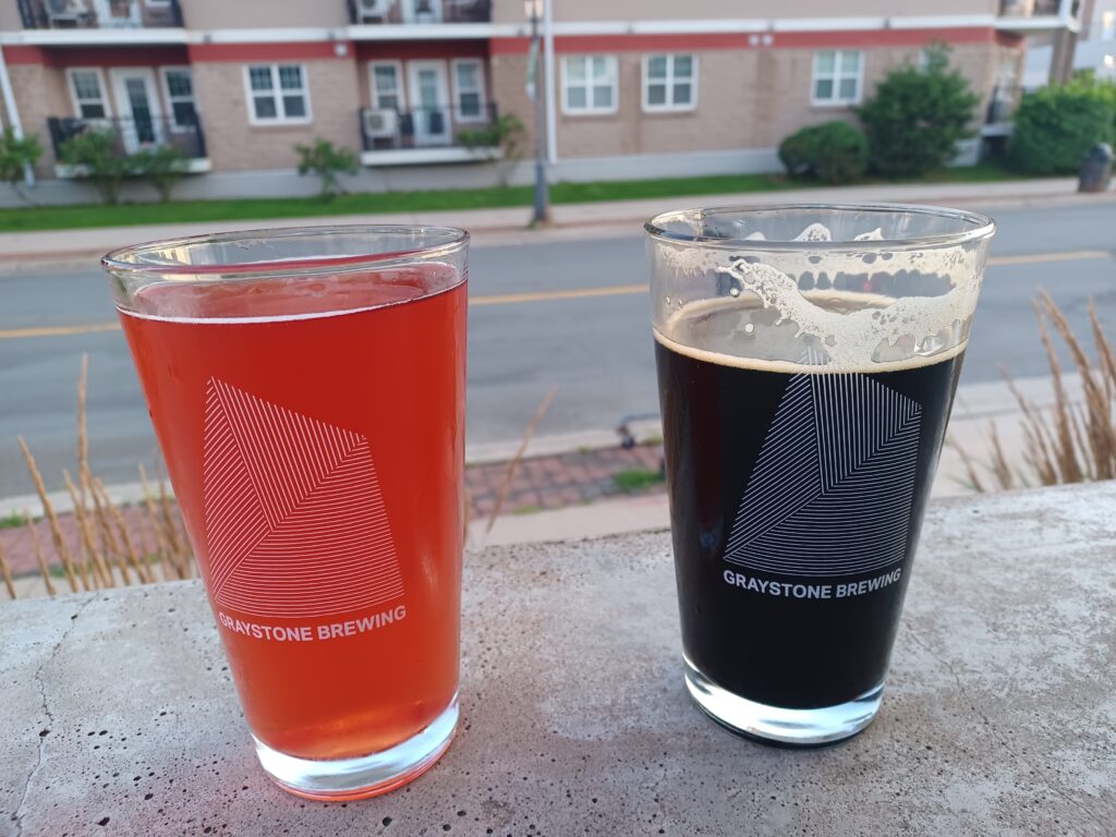 A red cider drink (left) and a dark brown craft beer (right). It says Graystone Brewing on both glasses.